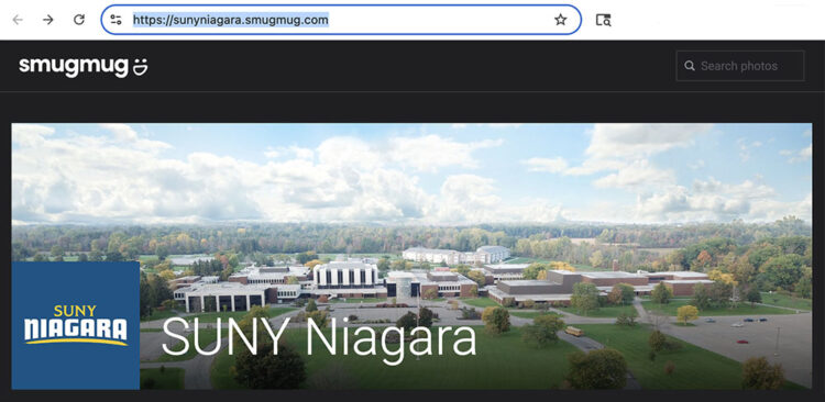 SUNY Niagara campus aerial view on SmugMug website, showing multiple buildings, green lawns, parking lots, and the surrounding wooded area under a cloudy sky.