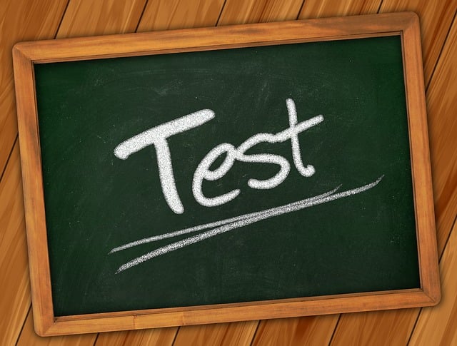 A chalkboard with the word Test written in white chalk, underlined, and framed with wood. The board is placed on a wooden surface.