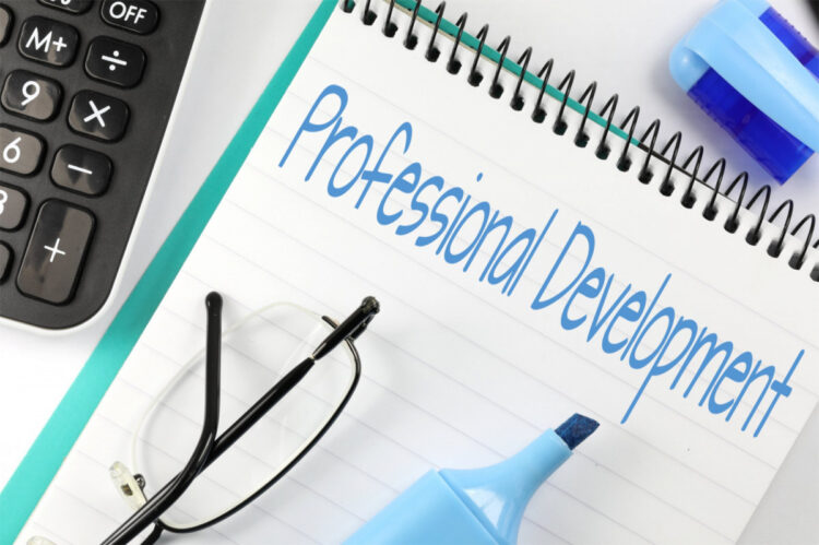 A notebook with Professional Development written on it, next to a calculator, eyeglasses, a blue highlighter, and an eraser.