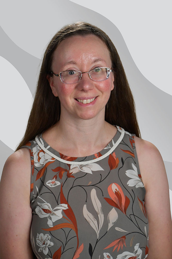 A woman with long brown hair, glasses, and a sleeveless floral top smiles at the camera against a gray background with abstract wave patterns.