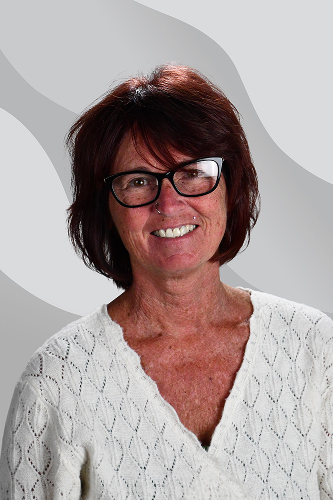 A woman with reddish-brown hair and glasses smiling at the camera.
